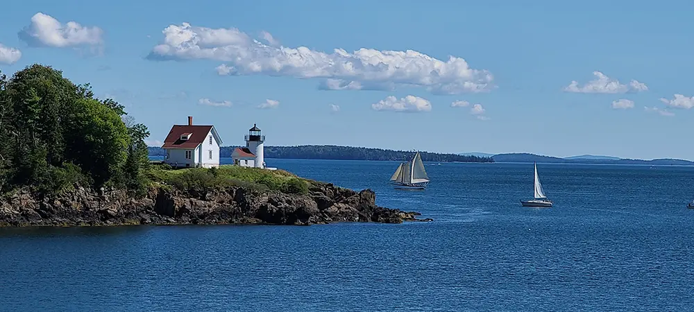 Cutler Island Lighthouse with sailboats floating by. Maine coast Camden