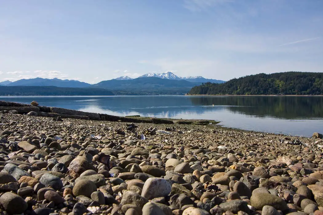 Hood Canal Washington with Olympic Mountains in background with rocky beach reflection shot. The best photography spots in Olympic National Park