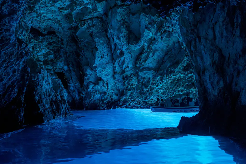 Tourists on a boat in serene blue cave near Komiza island in summer. The best Photography spots in Croatia