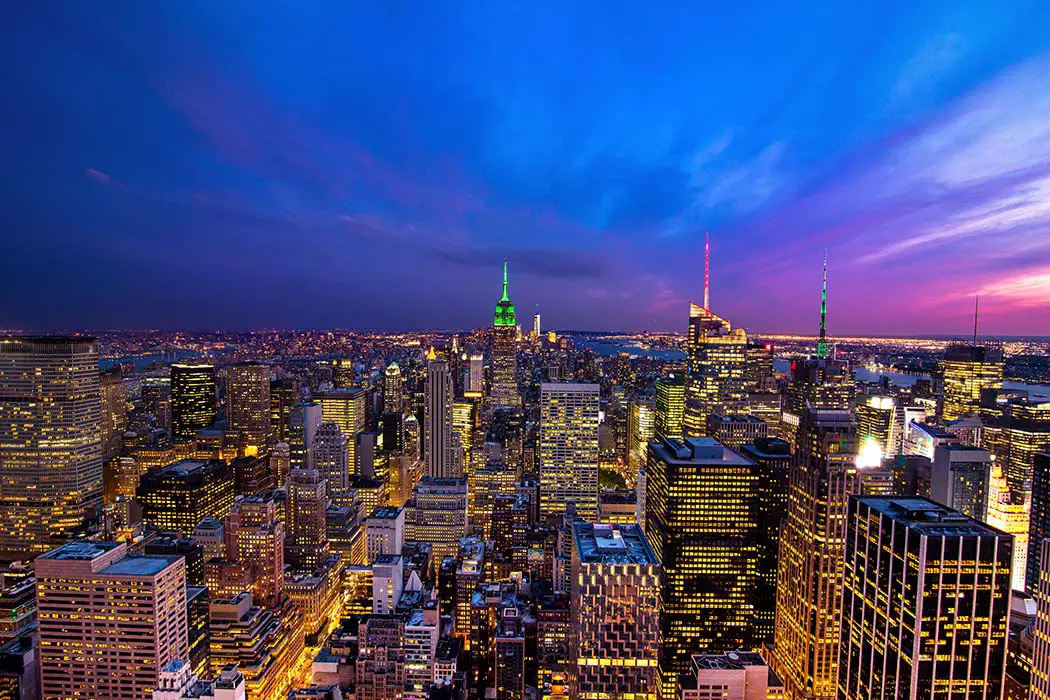View from Rockefeller Center over New York skyline at night with blue and purple skies. The famous landscape photography locations. Best Cities To Photograph in USA
