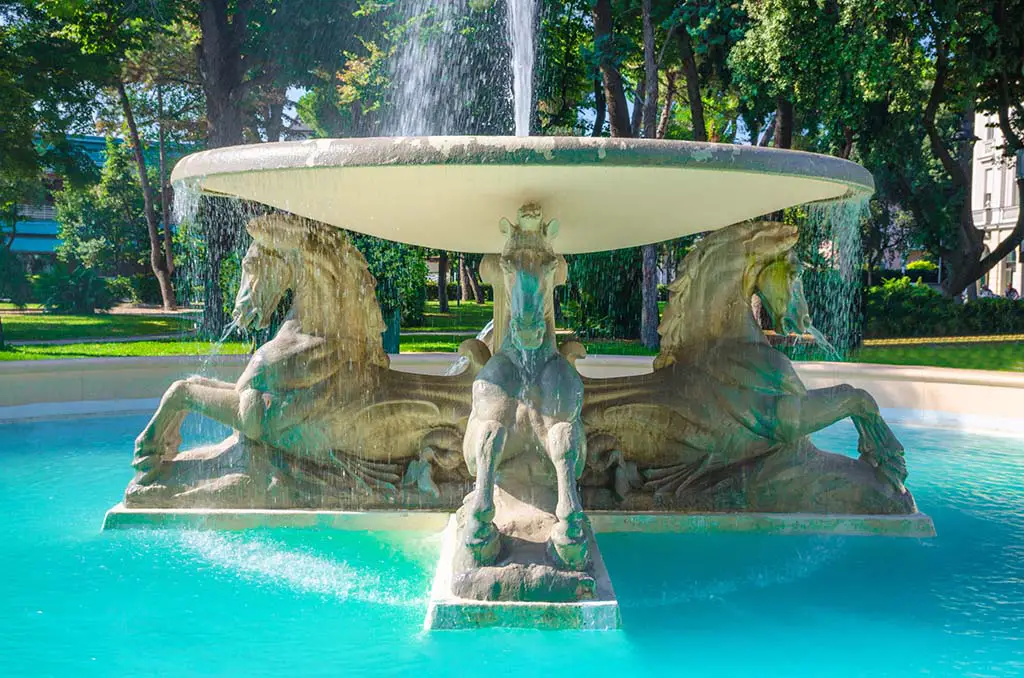 Quattro cavalli Four horses fountain with turquoise water in Parco Federico Fellini park with green trees in touristic city centre