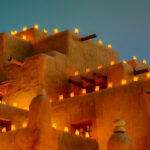 Large adobe building with holiday lights at dusk in Santa Fe. Best Photography Spots in Santa Fe New Mexico.